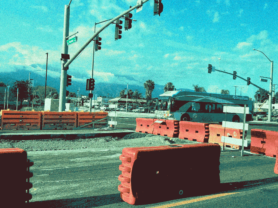 another bus passes the median construction. mountains in the distance