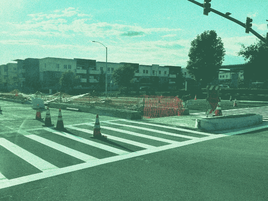 median with curbs installed, including a curb that protects the middle of the crosswalk. large apartment building in the background