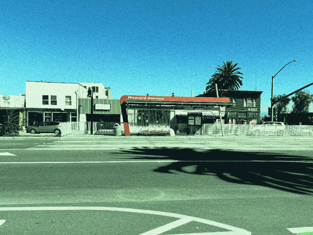 bus station with a fence on one side, facing the bus lanes. a large sign overhead reads  Howard avenue